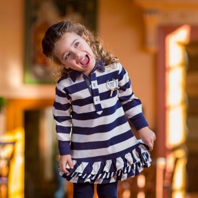 Striped knit dress with tights, seam at the hip with frills, collar and front opening with customized buttons. Decoration with Tutto Piccolo pattern and bow. AW18 5234